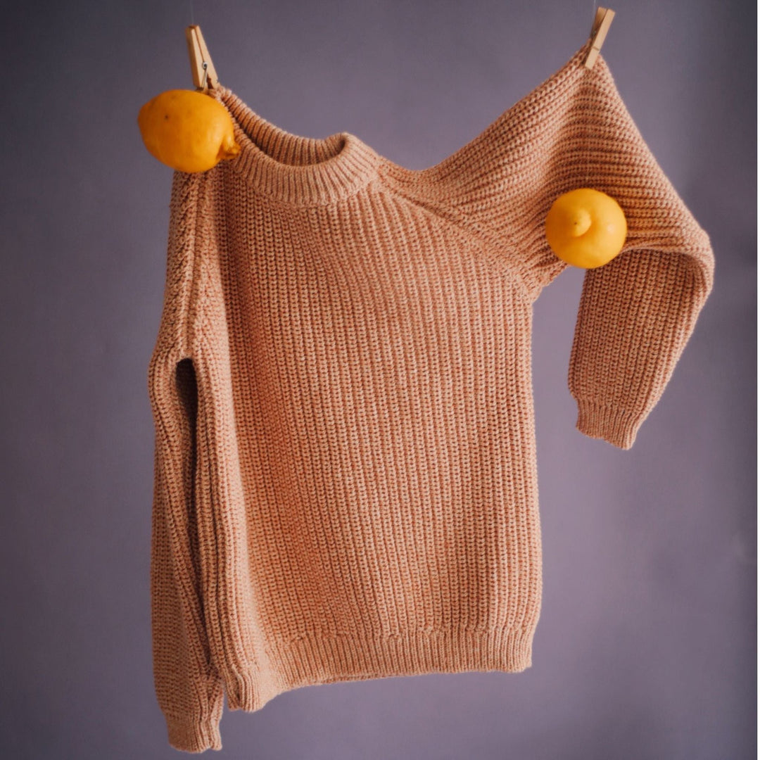 Beige cotton sweater on a line with fruit pegs, showing how to wash cotton