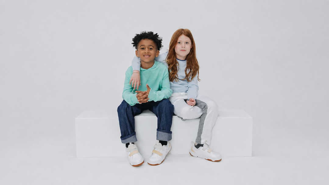 Boy and girl in soft organic cotton outfits from Firebird Kids, featuring a mint sweatshirt, denim, and colorblock joggers