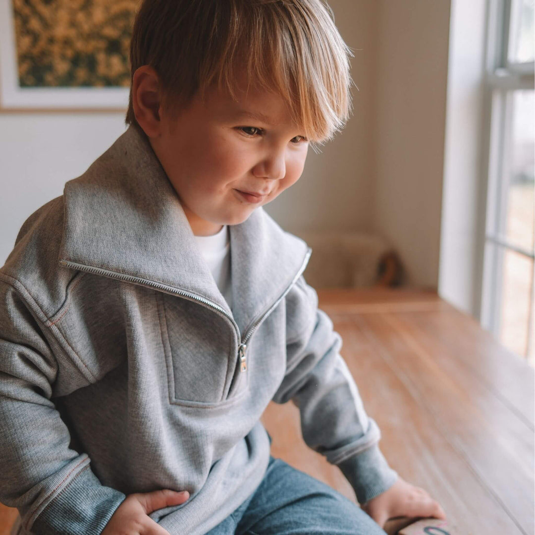 child in a grey half zip sweatshirtby Firebird Kids