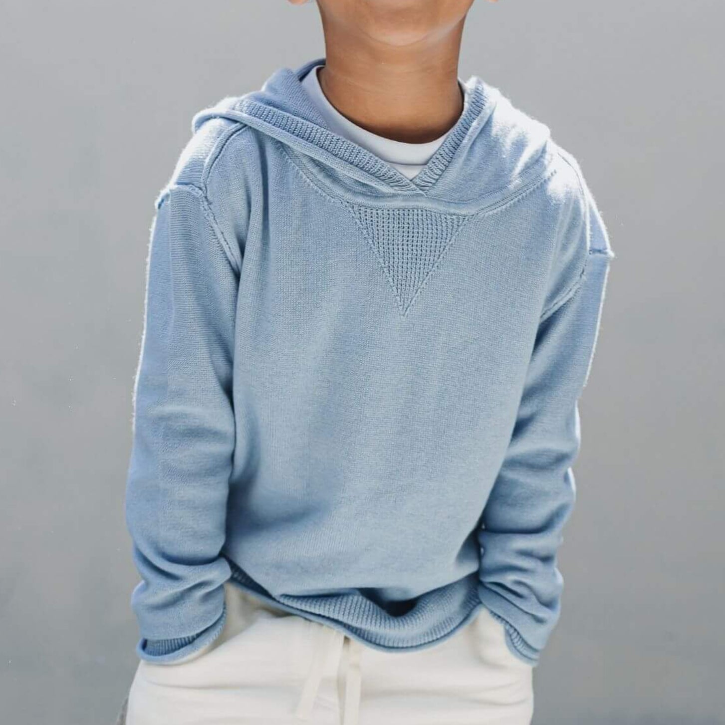 Close-up of a boy wearing the Firebird Kids soft blue cotton-cashmere hoodie sweater