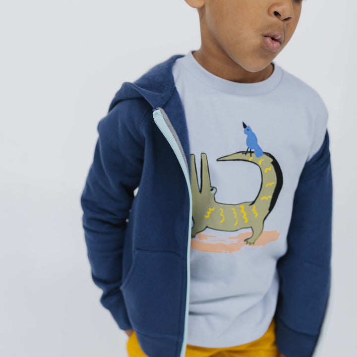 Boy wearing a T-shirt with a crocodile and bird graphic print