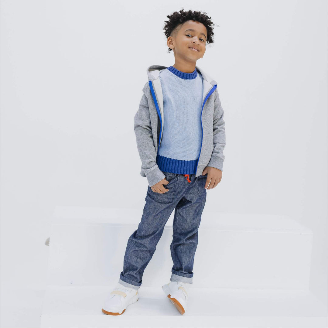 Boy wearing the Firebird Kids gray fleece zip hoodie with blue zipper and soft denim pants