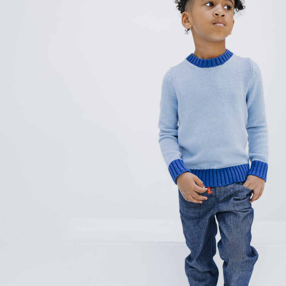 Boy wearing the light blue colorblock crewneck sweater with Firebird Kids dark denim pants