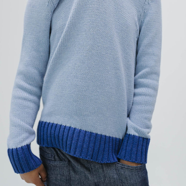 Close up of the organic cotton knit and cobalt ribbed hem and cuffs on the colorblock crewneck sweater