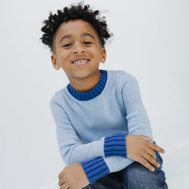 Smiling boy in the Firebird Kids colorblock crewneck sweater, light blue with cobalt trim