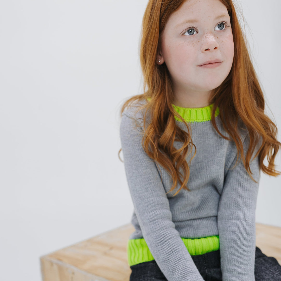 Girl seated in the heather grey colorblock crewneck sweater with neon yellow trim, Firebird Kids
