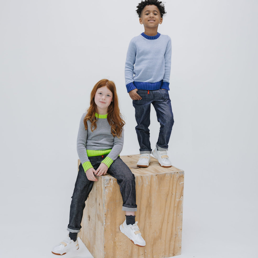 Girl seated in the heather grey colorblock crewneck sweater with a boy standing in the light blue colorway