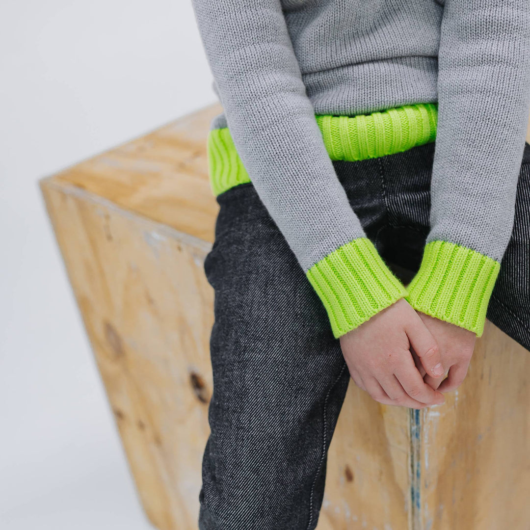 Close up of the neon yellow ribbed cuffs and hem on the heather grey organic cotton colorblock sweater