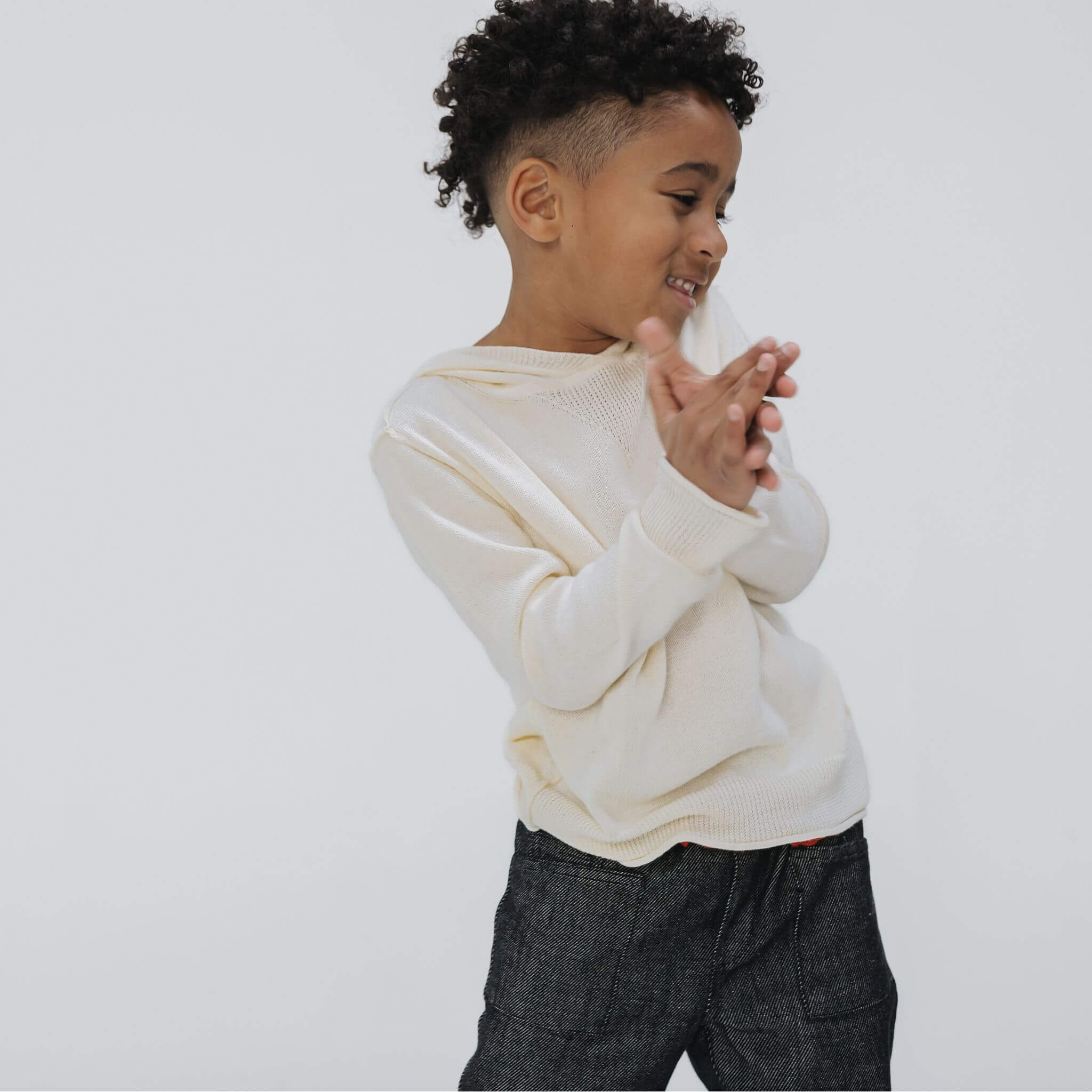 Front view of the Firebird Kids ivory cotton-cashmere hoodie sweater on a dancing boy