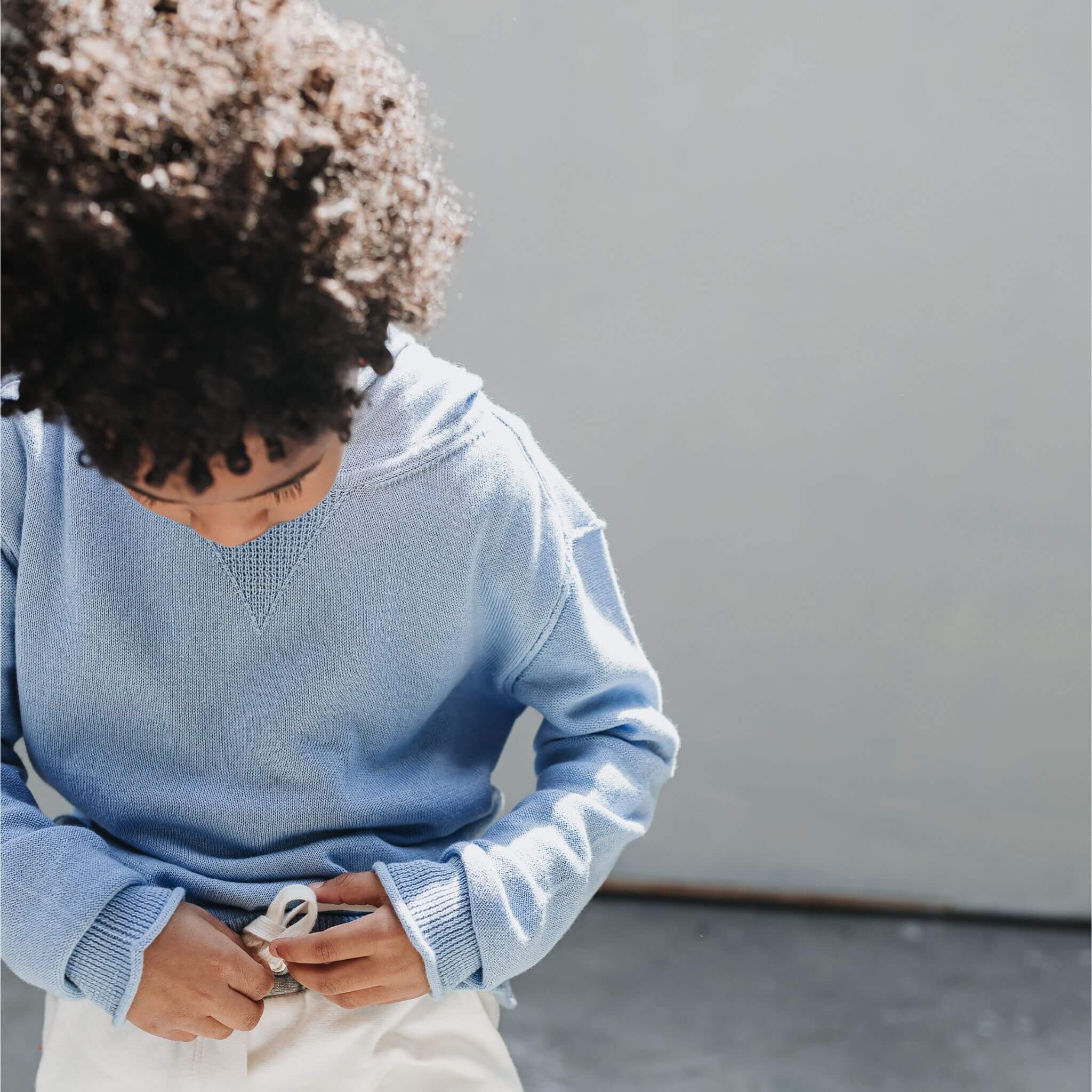 Close-up of a child wearing the Firebird Kids soft blue cotton-cashmere hoodie sweater