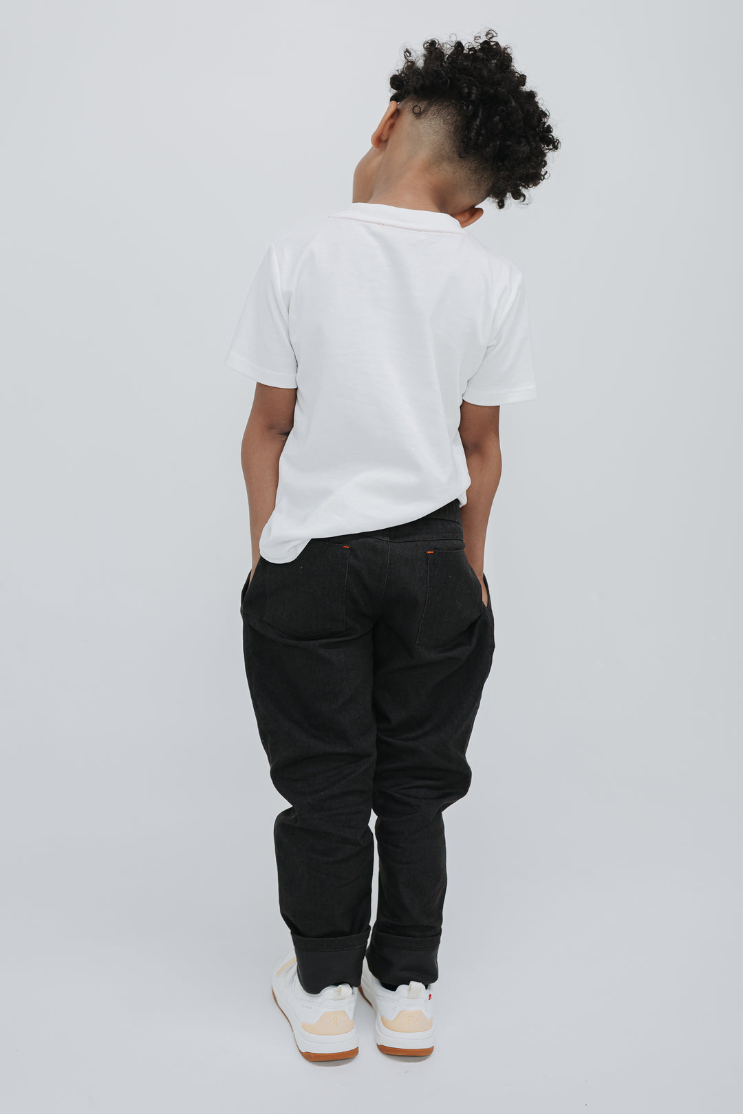 Back view of a boy in black drill pants showing the two back patch pockets