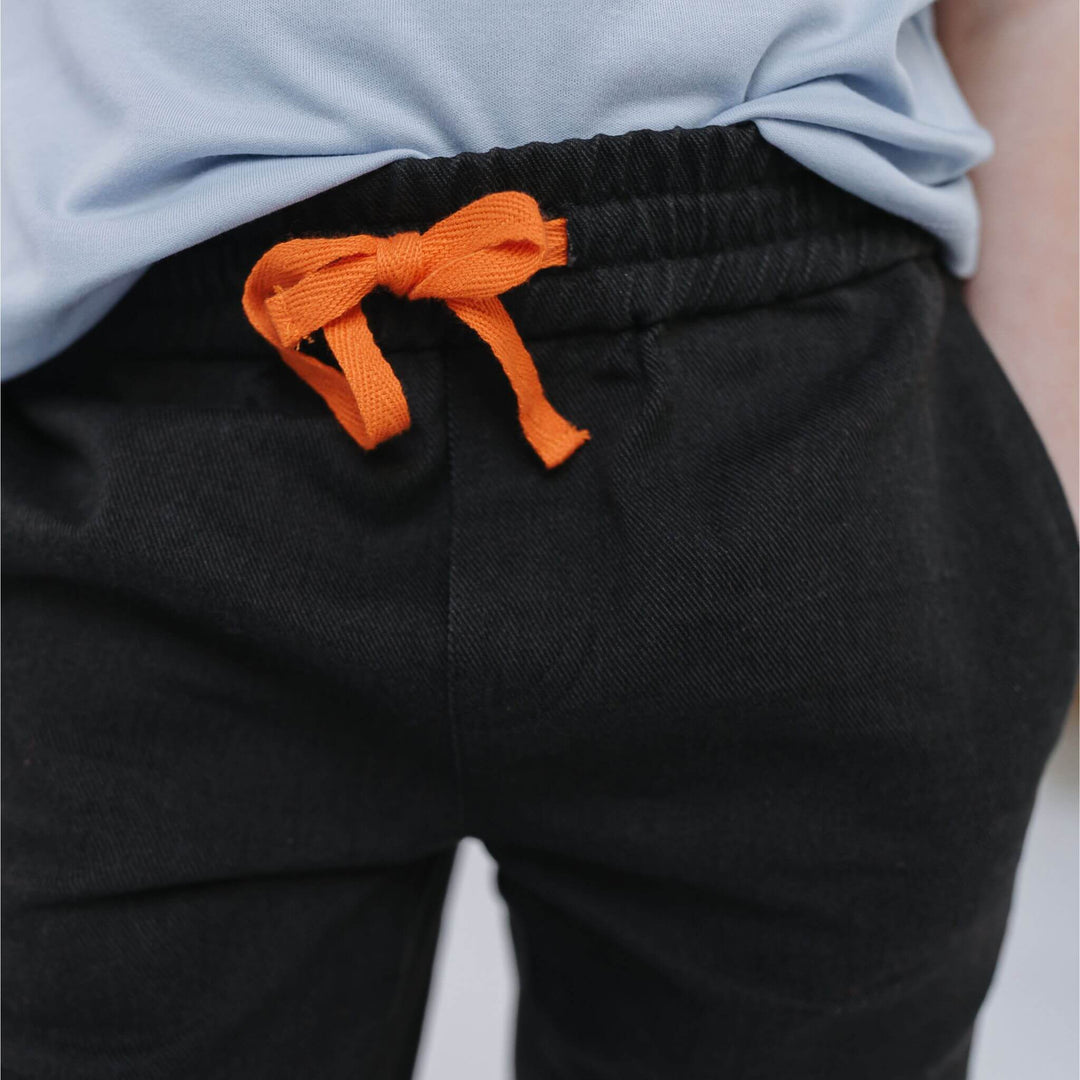Close-up of the elastic waistband and orange drawstring on Firebird Kids' black Vintage Drill Pant
