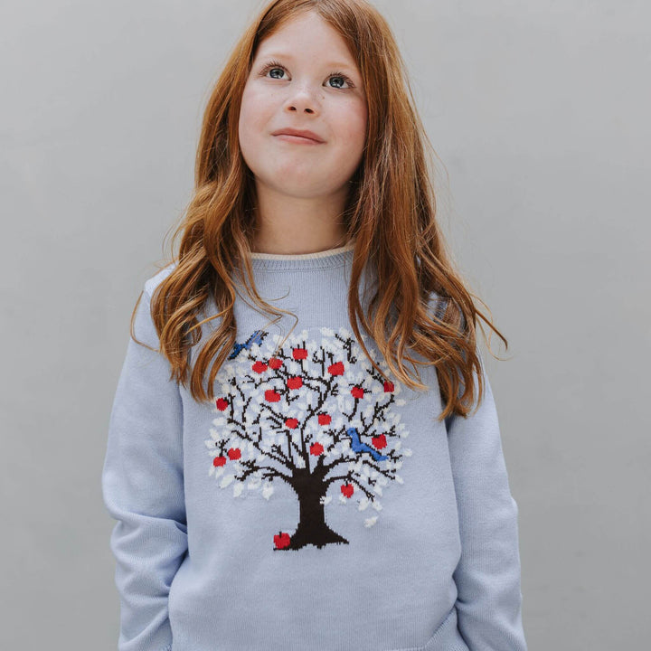 Girl wearing the Firebird Kids dusty blue organic cotton Tree Intarsia Sweater