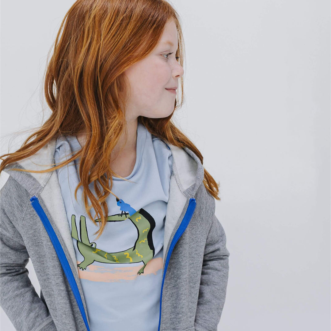 Girl wearing a T-shirt with a crocodile and bird graphic print