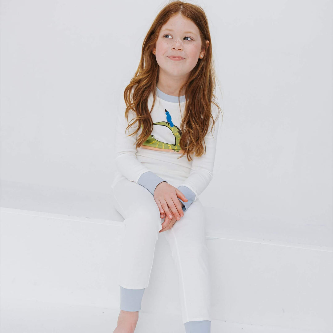 Girl wearing crocodile pajamas with soft blue cuffs