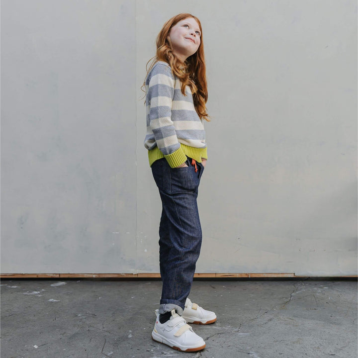 Girl wearing the Firebird Kids outfit of yellow and ivory striped organic cotton crewneck sweater and denim pants 
