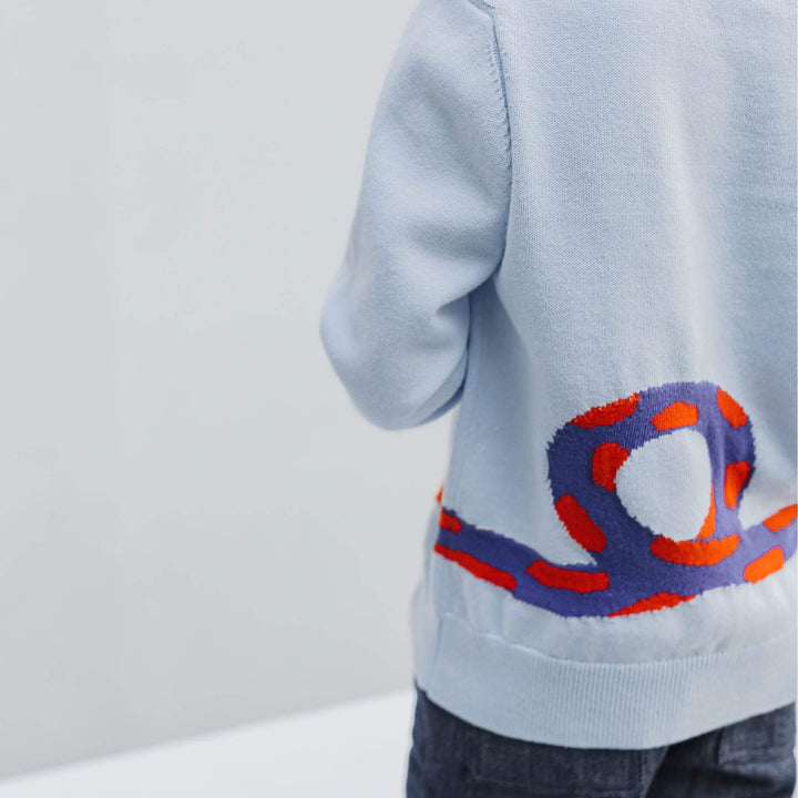 Close-up of the knitted-in intarsia snake on the back of the powder blue organic cotton kids sweater