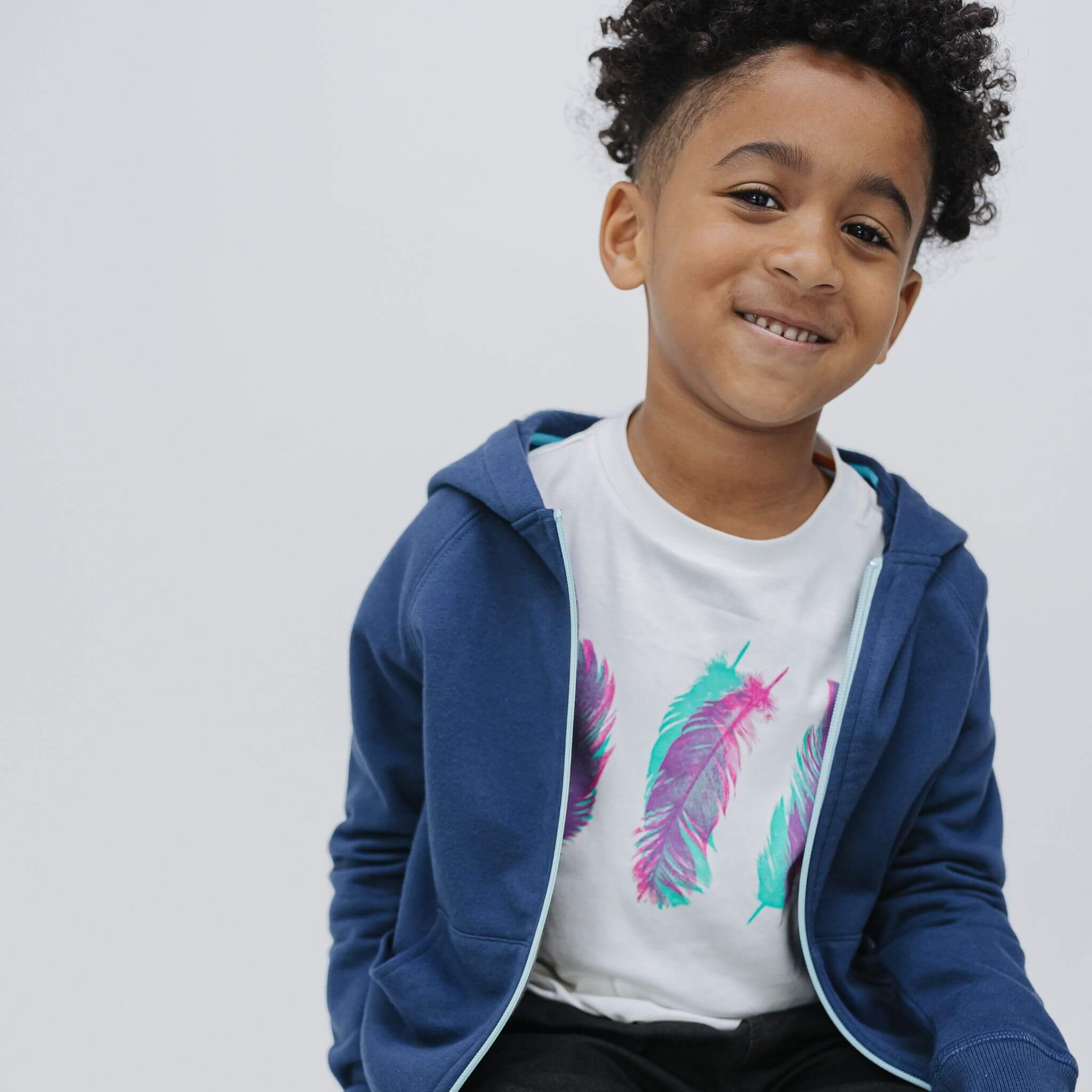 Three Feathers organic cotton kids tee layered under a navy zip hoodie