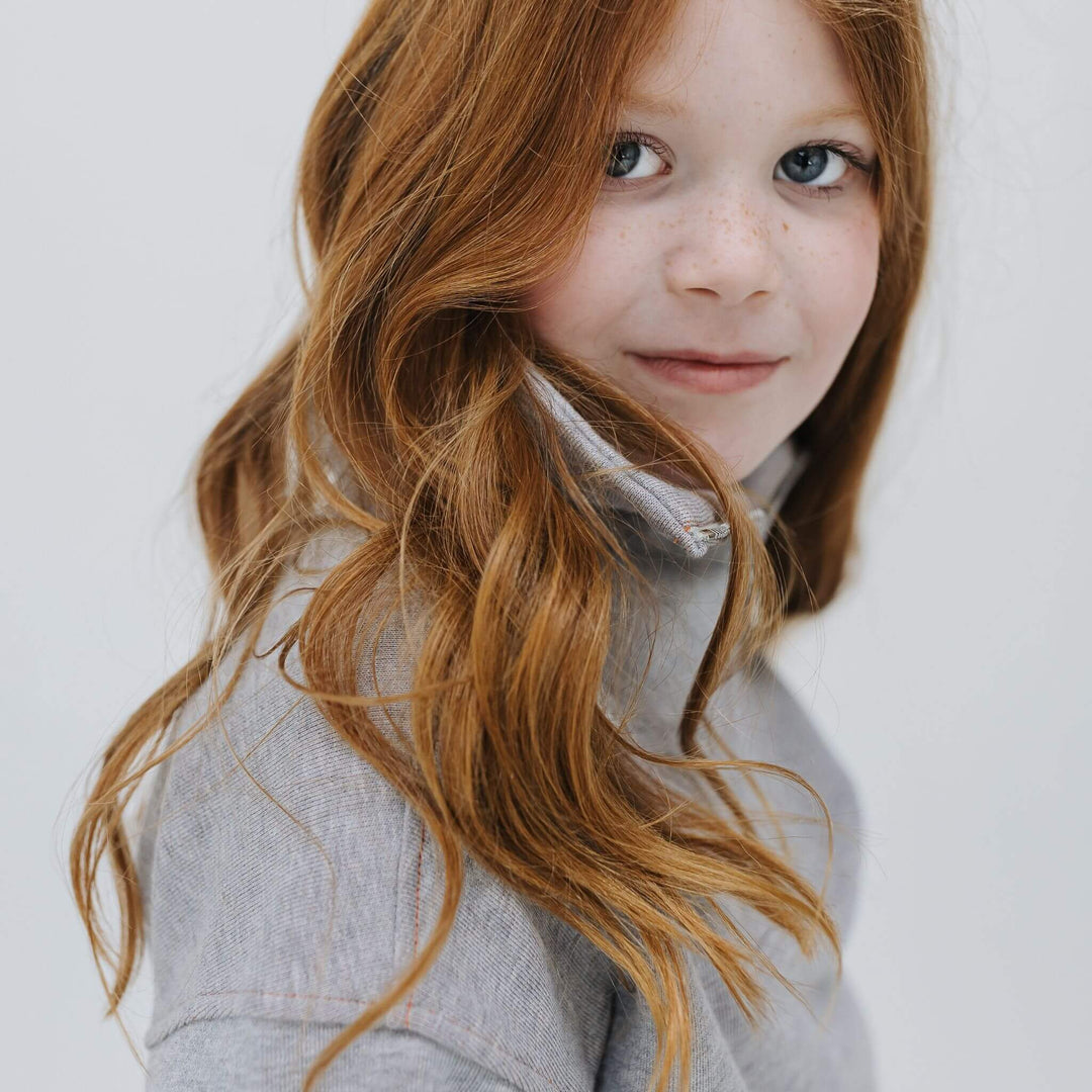 Close-up of the mockneck collar and zipper on the gray organic cotton half-zip sweatshirt on a girl 