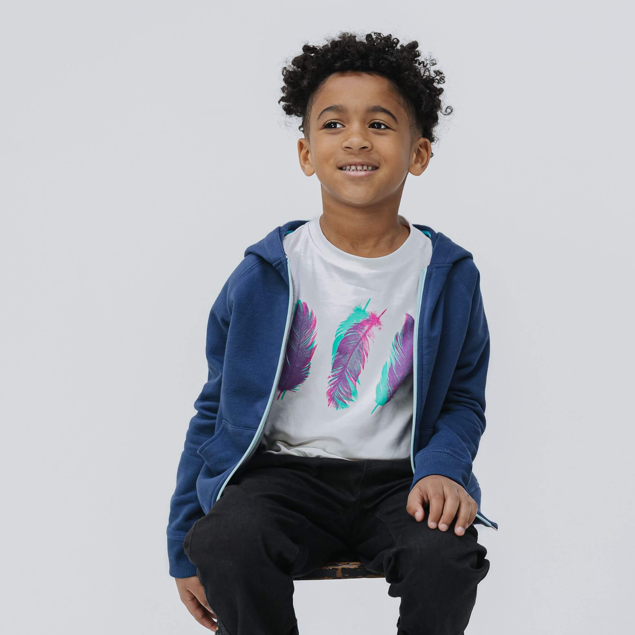 Boy seated in the Firebird Kids navy organic cotton zip hoodie