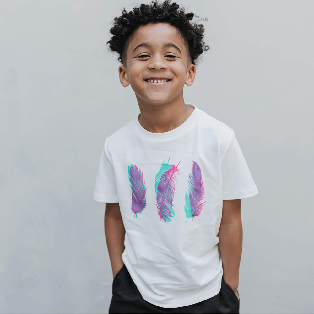 Child wearing the Firebird Kids Three Feathers organic cotton graphic tee in white
