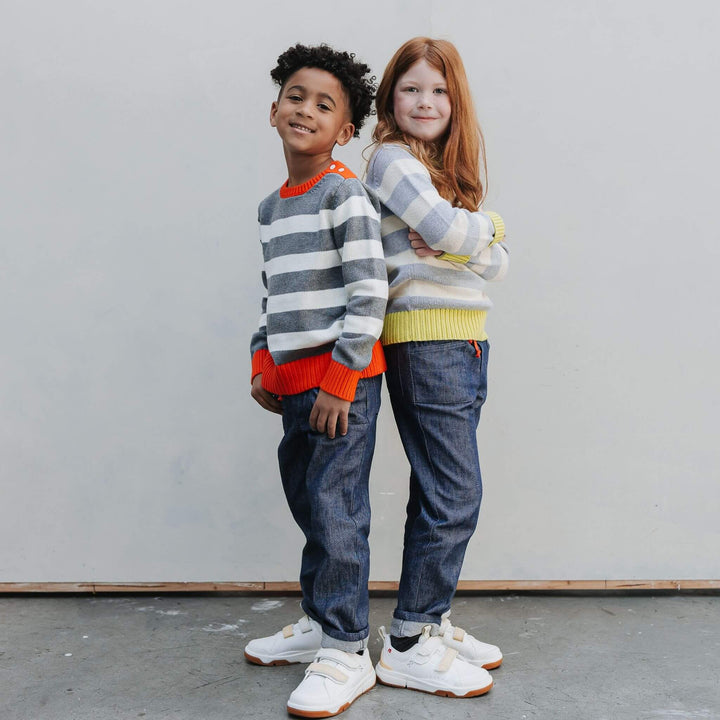 Two children wearing Firebird Kids organic cotton striped sweaters with yellow and red trim