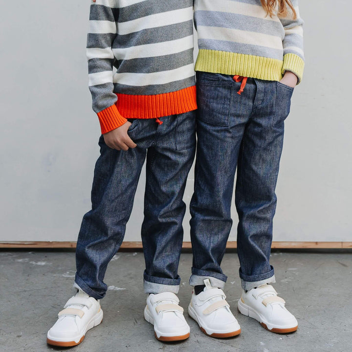 A boy and a girl standing side by side wearing dark blue soft denim jeans
