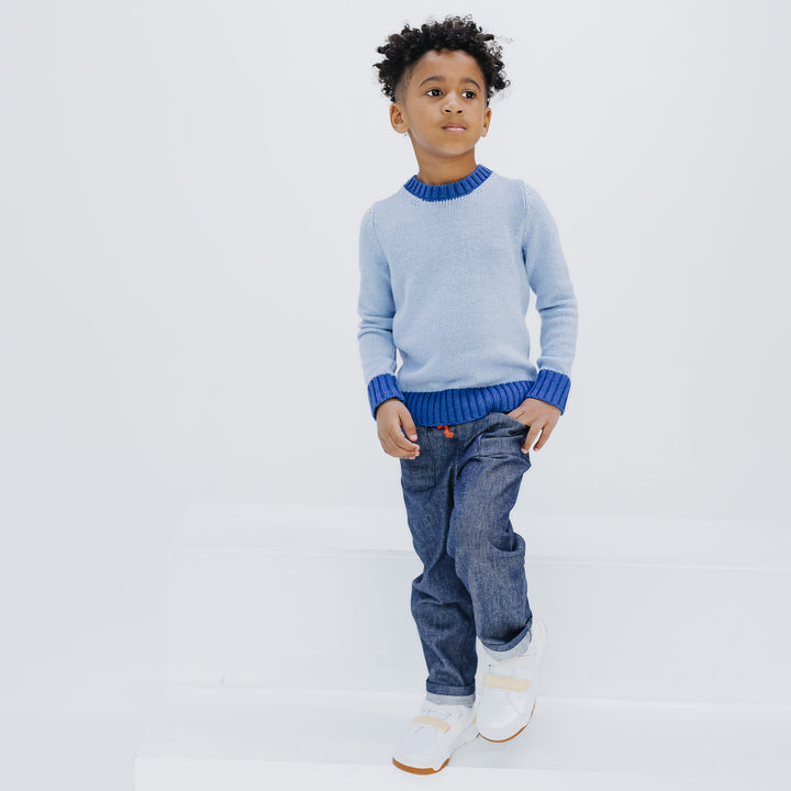 Boy wearing the Firebird Kids Studio Denim Pant in navy with the light blue colorblock crewneck sweater, full look