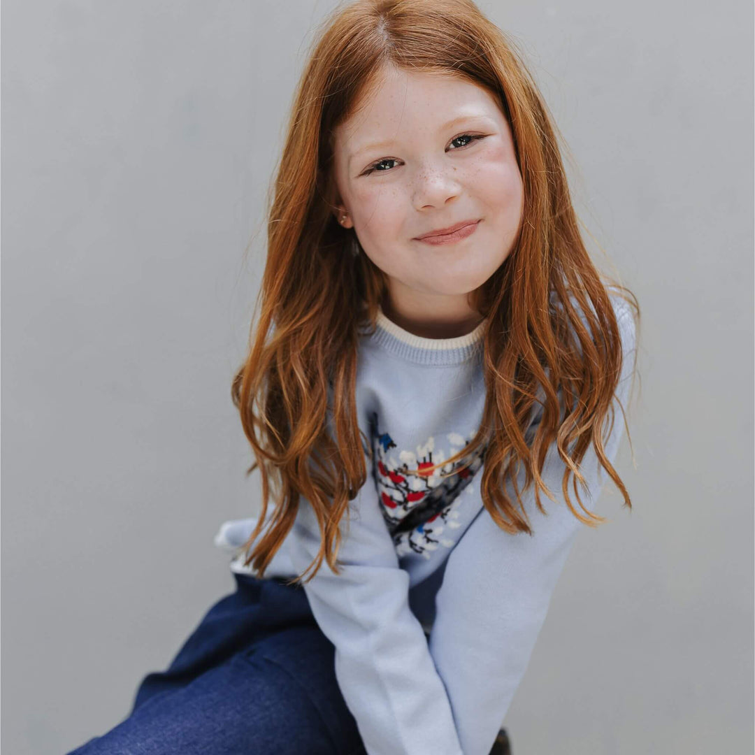 Girl wearing the Firebird Kids dusty blue organic cotton Tree Intarsia Sweater